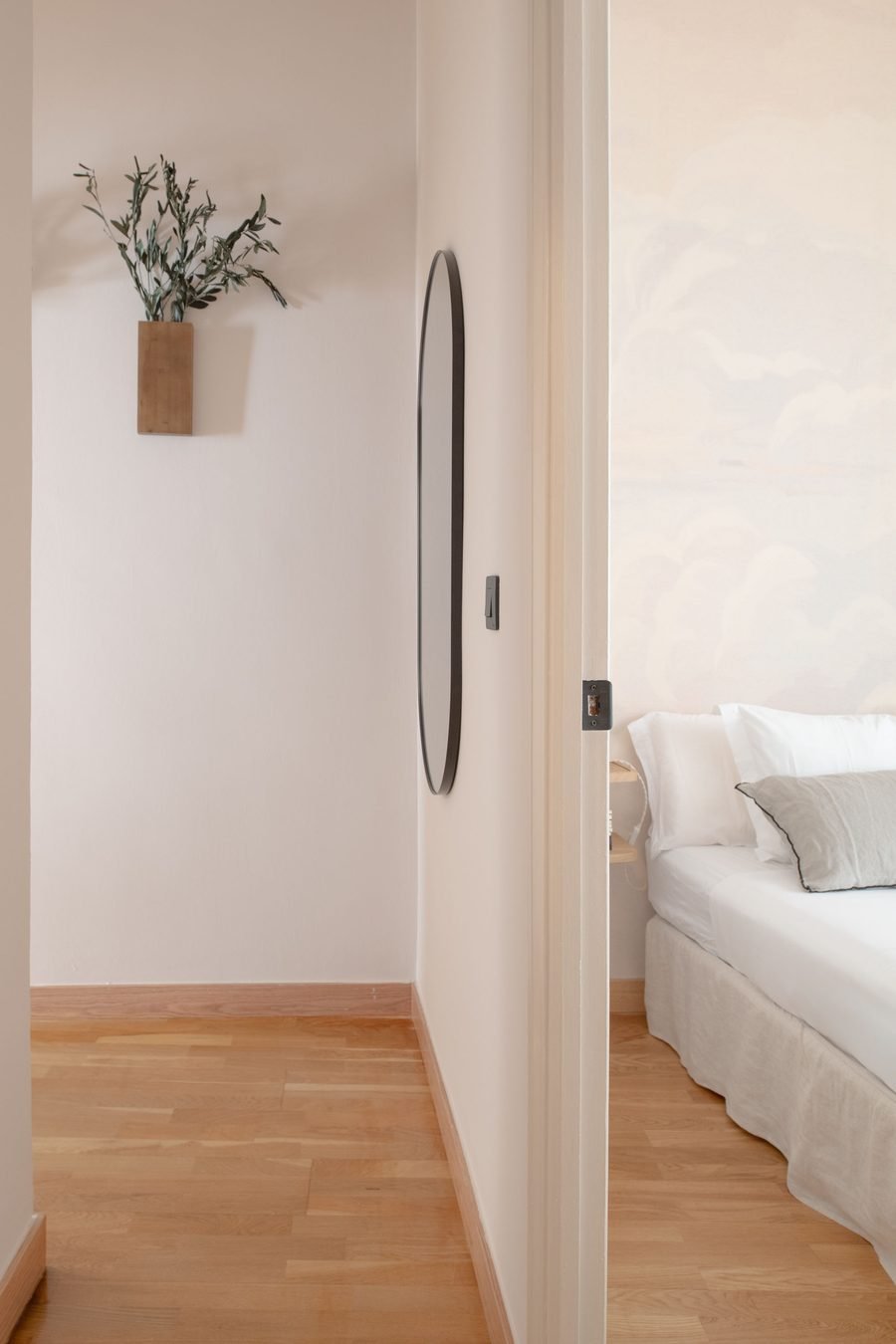 Pasillo con espejo ovalado y vista al dormitorio