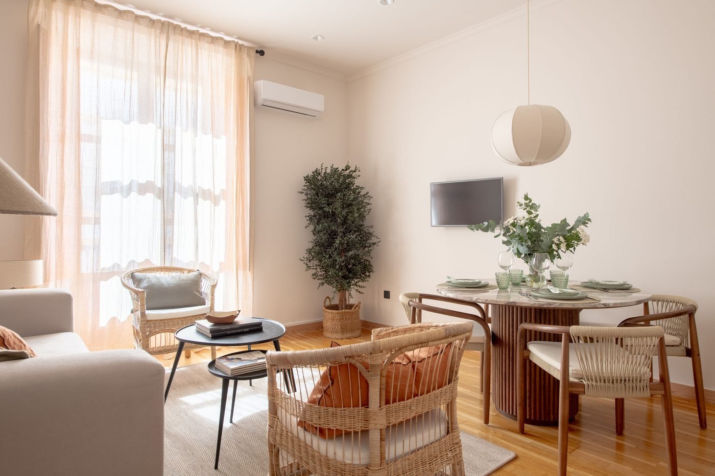 Salón-comedor hacia la ventana, con cortinas de lino y butacas de mimbre